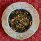 teacup full of gold-tipped black tea leaves with citrus peel and osmanthus flowers