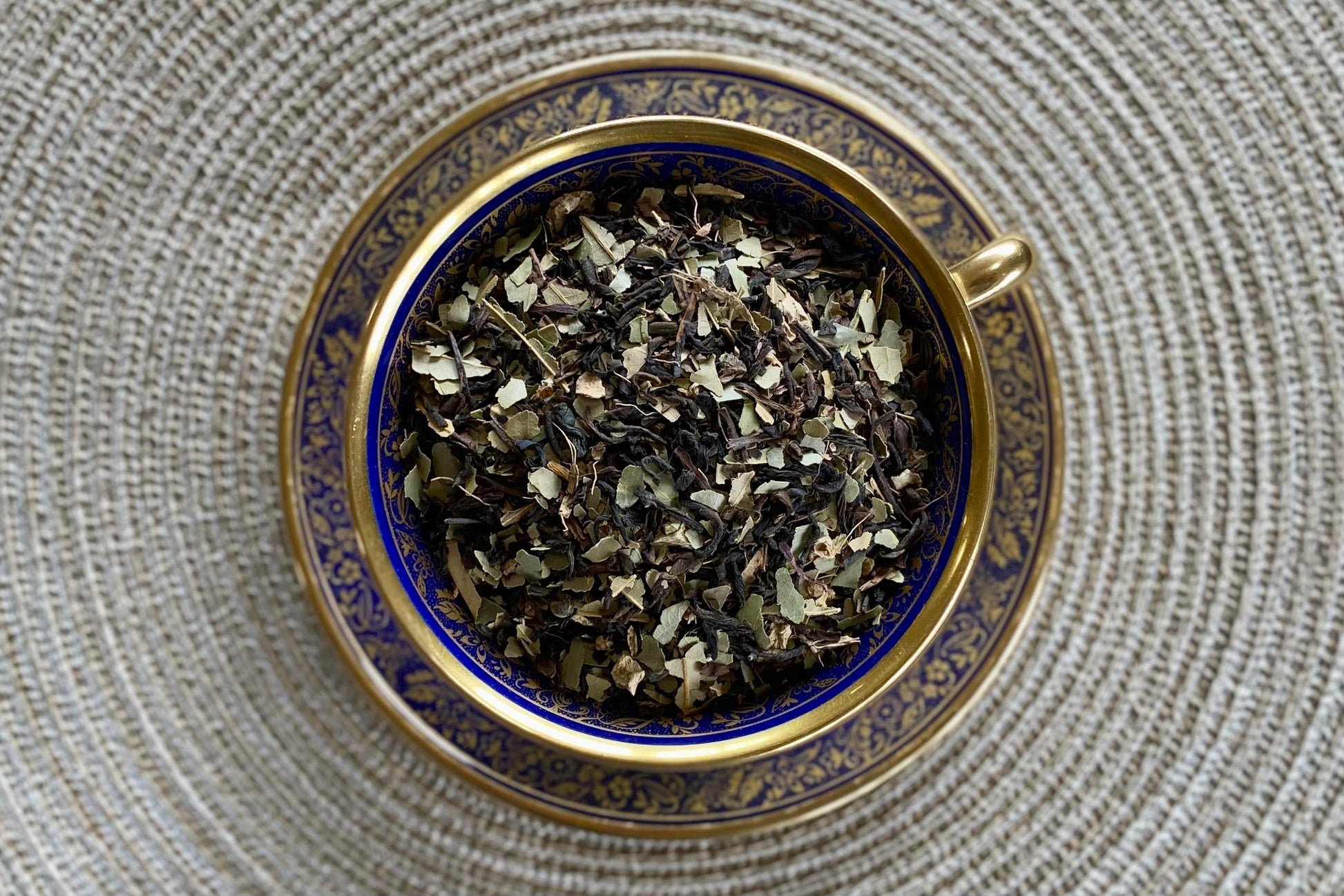 teacup full of black tea with cinnamon leaf