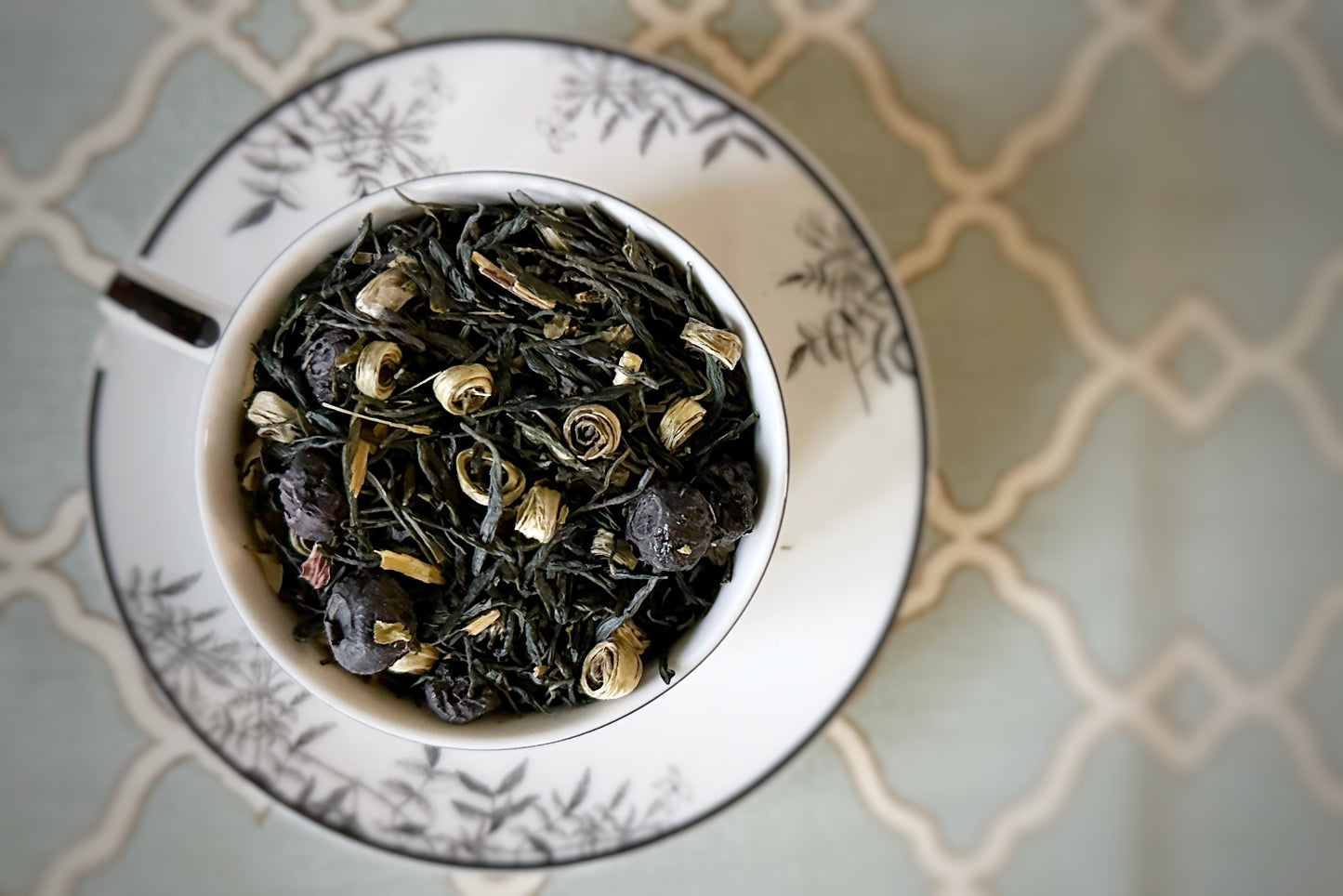 teacup full of green tea and blueberries